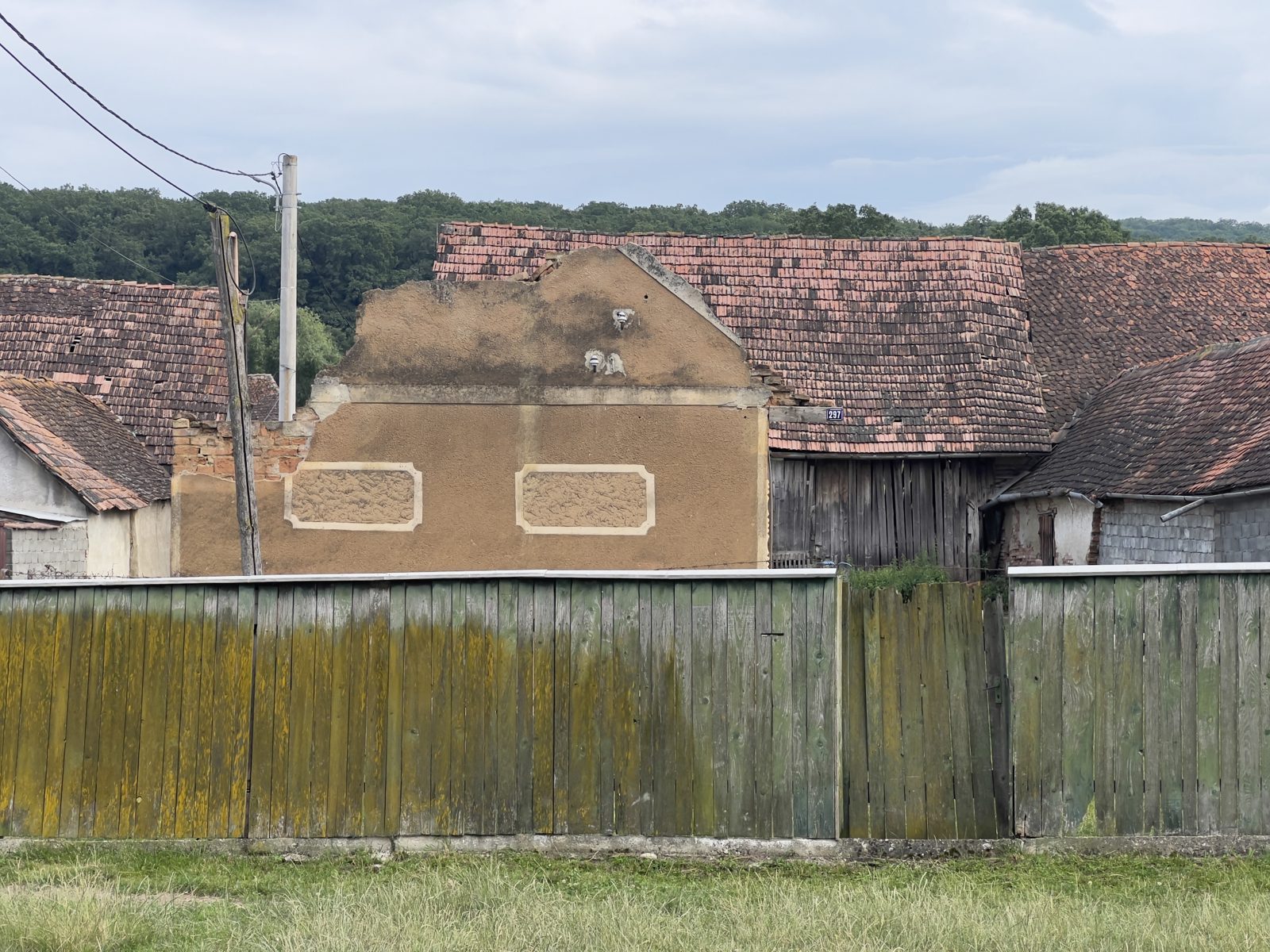 Fronton săsesc ornamentat, lângă o casă în cădere, în Dacia